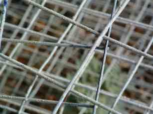 The welded wire that goes into the cement or mortar behind the wall needs be heavier than chicken wire, but doesn't need to be rebar if the wall is low.