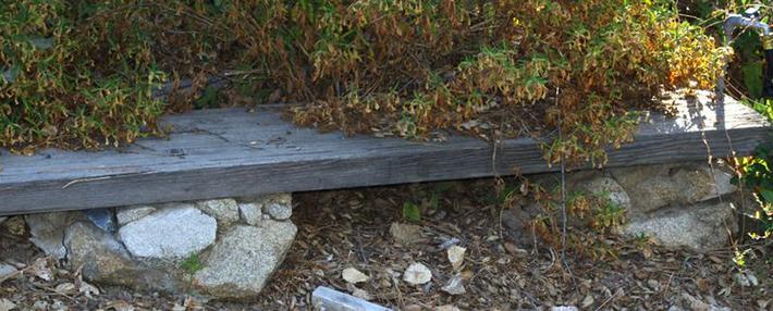 Plank mortared to rock pillar.