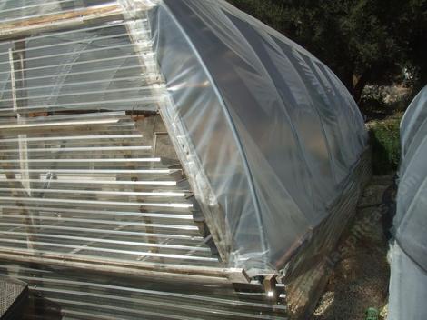 Greenhouse sides can be of pvc, polycarbonate, fiberglass or poly. We've found the best was polycarbonate for the first couple of feet.  The rest of the greenhouse can be poly. Notice the polycarbonate vent. Greenhouses have to be vented. - grid24_12