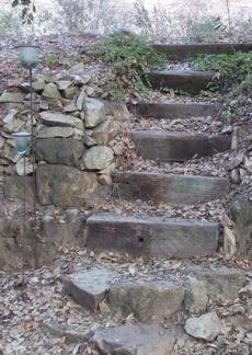 Short sections of  railroad ties make good steps within the dry stack walls. Either drive some nails into the bottom of each and cement them into place or drill a couple of holes through them and drive a piece of rebar through them. - grid24_6