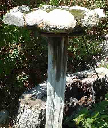 A rock/concrete bird bath on a wooden post. This birdbath worked well for about 5 years then the post fell over. - grid24_12